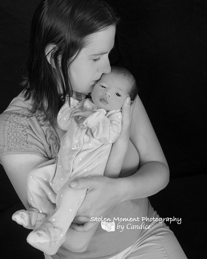 mom kissing newborn daughter's forehead