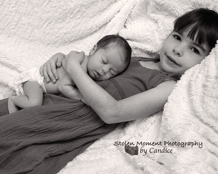Older sister holding her newborn sister while she sleeps