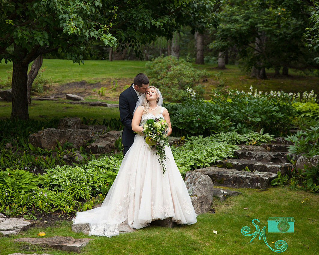 Groom kissing bride's forehead in a beautiful wooded area