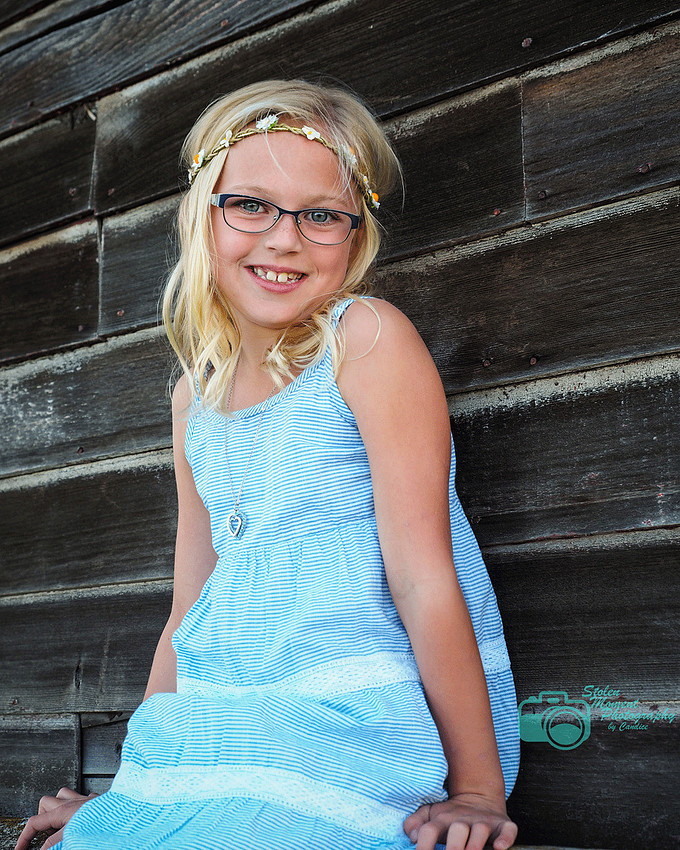 girl in sundress sitting outside old barn