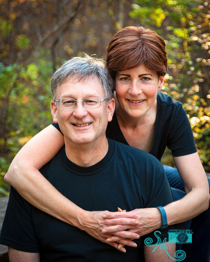 husband and wife posing in front of fall leaves
