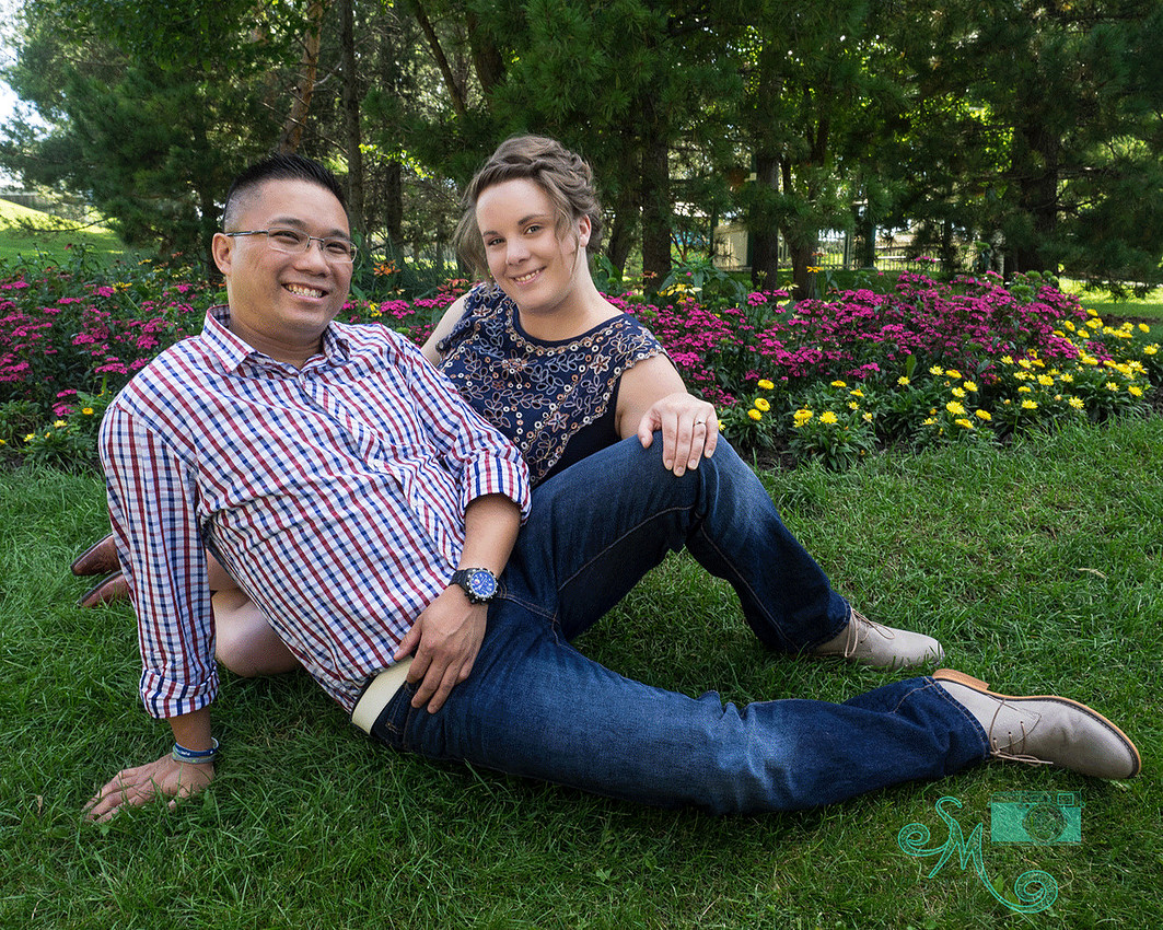 couple sitting on the ground in front of flowers