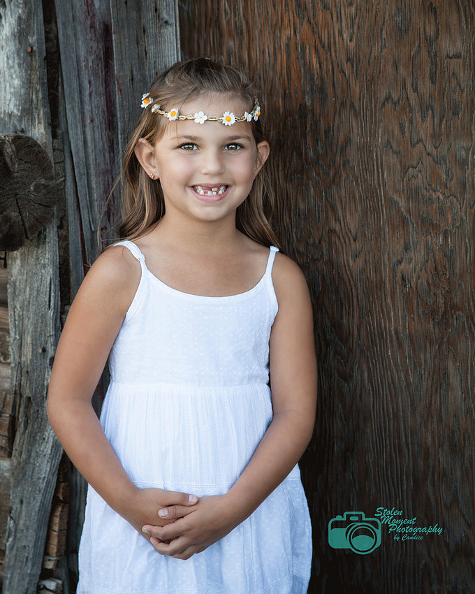 girl in white sundress standing outside a barn
