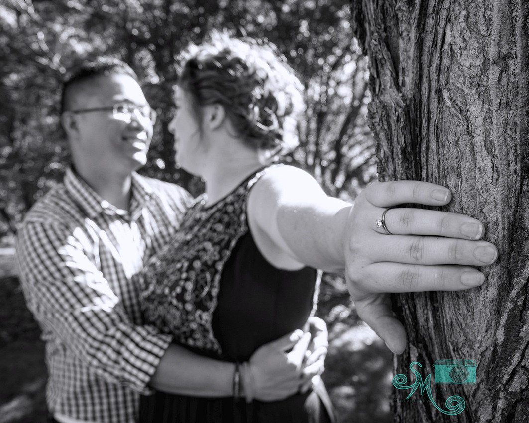 couple embracing in background while her engagement ring takes centre stage