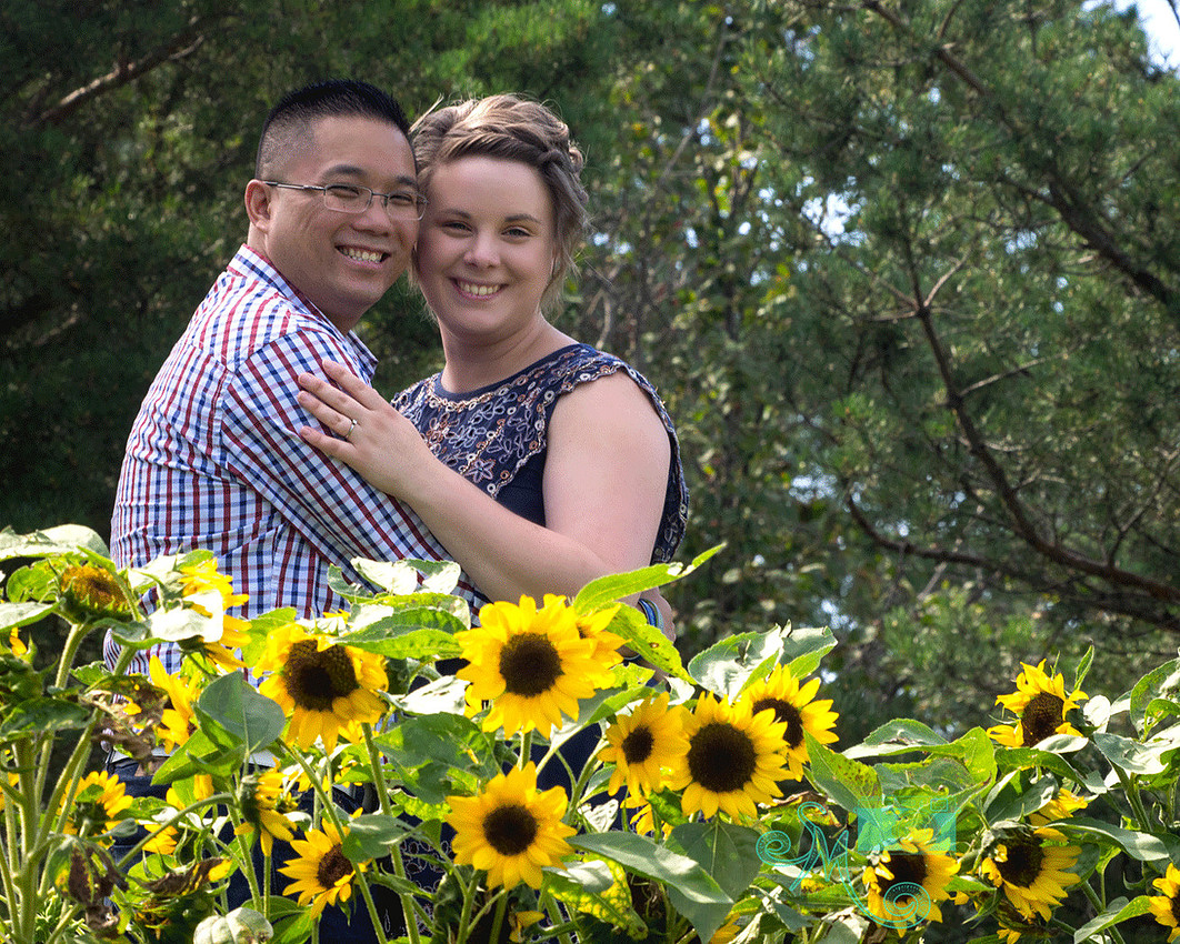 couple embracing behind some sunflowers
