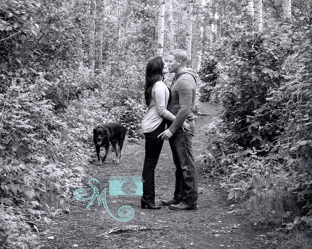 couple kissing on path with dog in background