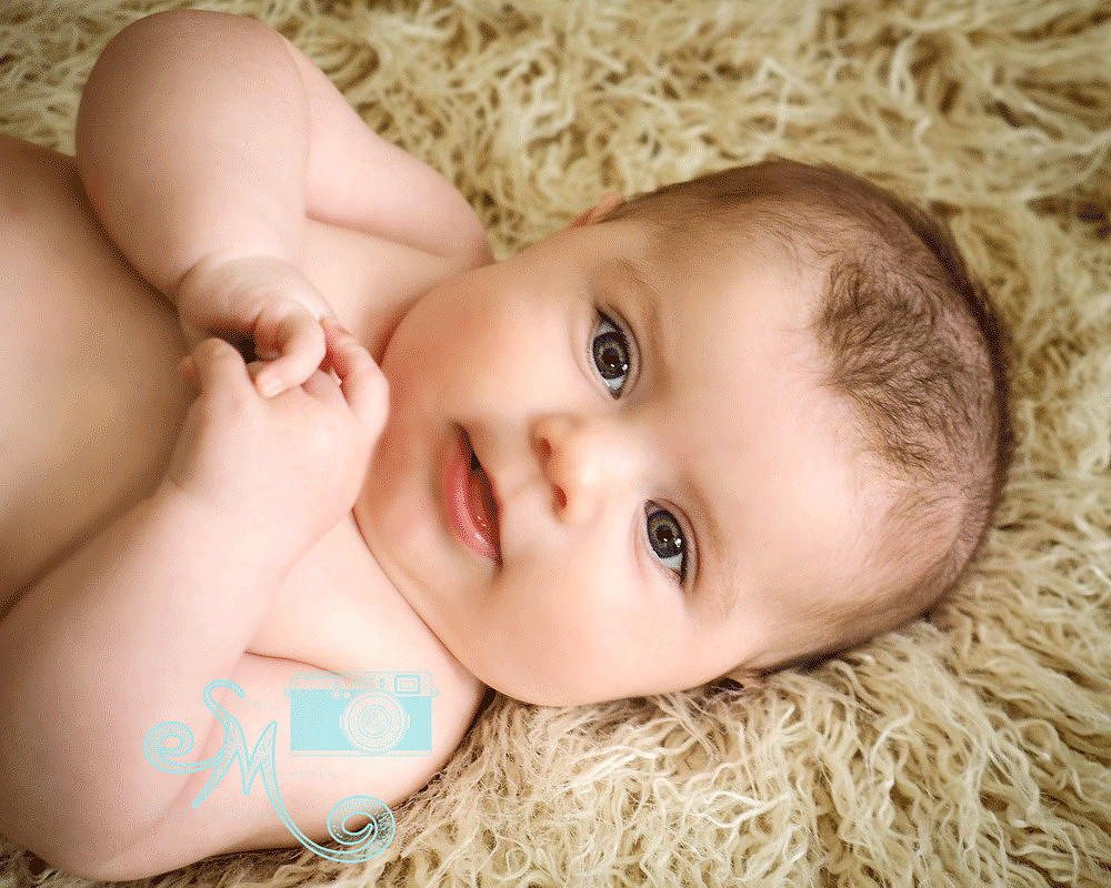 baby smiling up at camera while lying on back