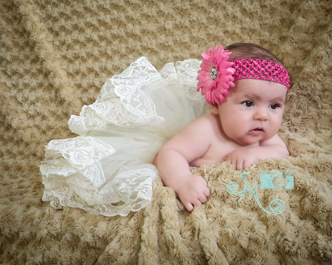 baby in tutu with flower headband laying on her tummy