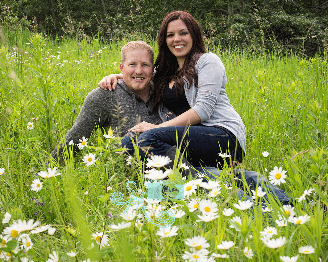 couple sitting on ground amid the daisies
