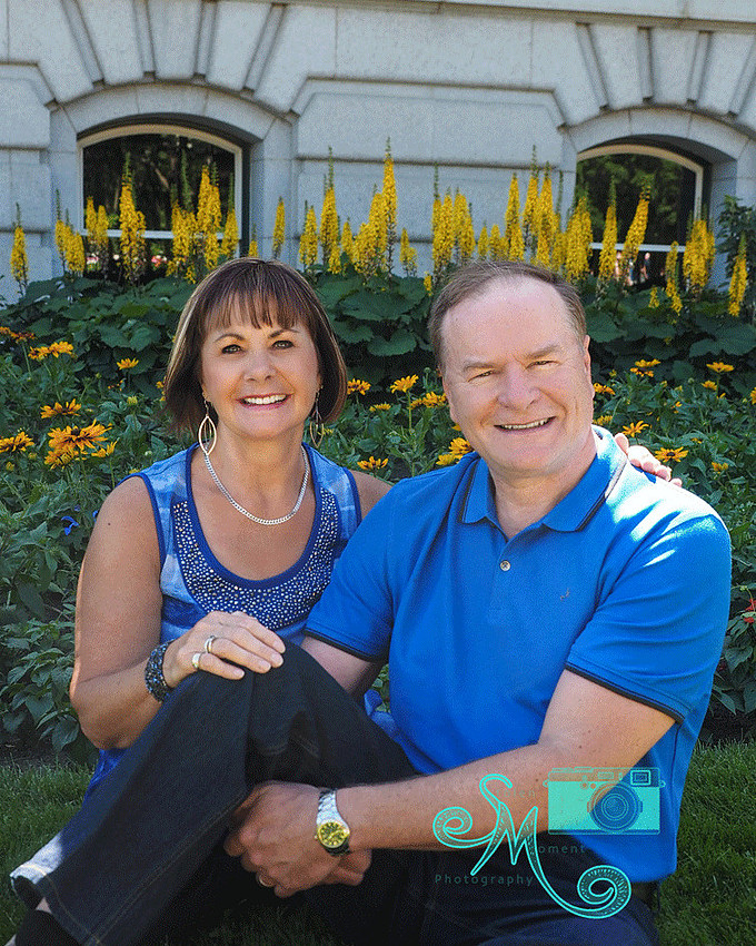 couple sitting in front of flowers