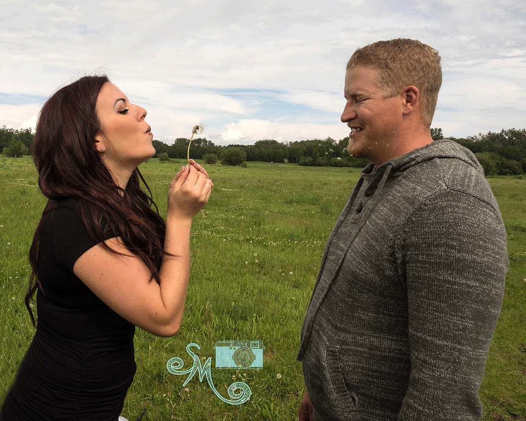 woman blowing dandelion fluff at fiance