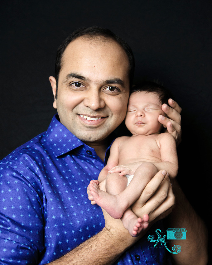 a proud dad holds his newborn son up by his face