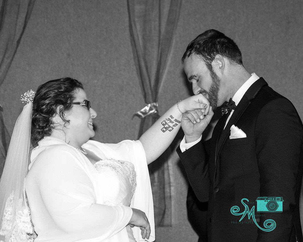 groom kissing bride's hand after placing ring on her finger