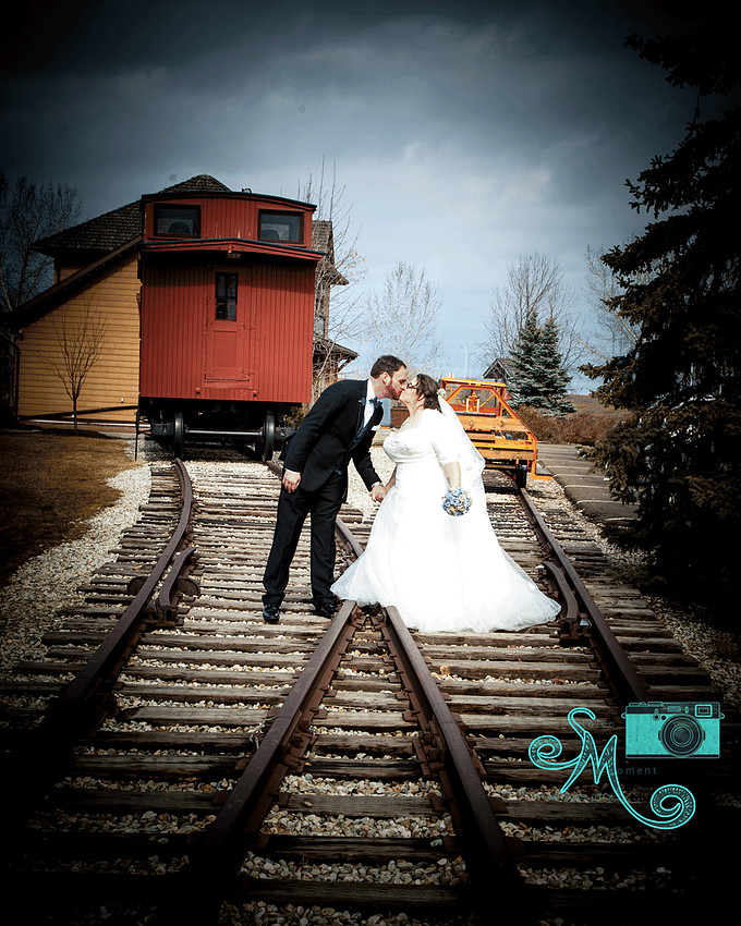 bride and groom on railway tracks kissing