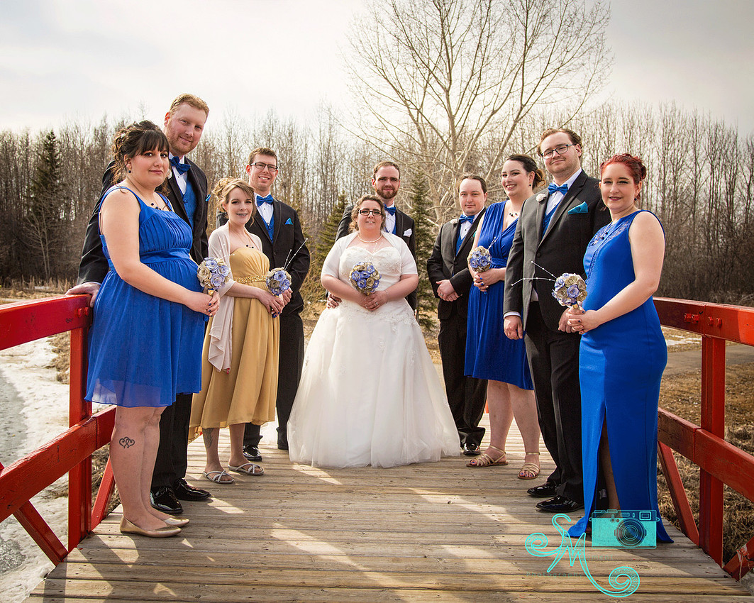 wedding party standing on a bridge