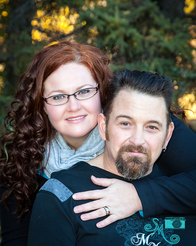 a couple pose among the fall leaves