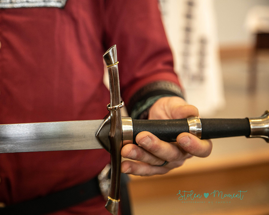 The groom's ring is presented by a guard on the bride's sword