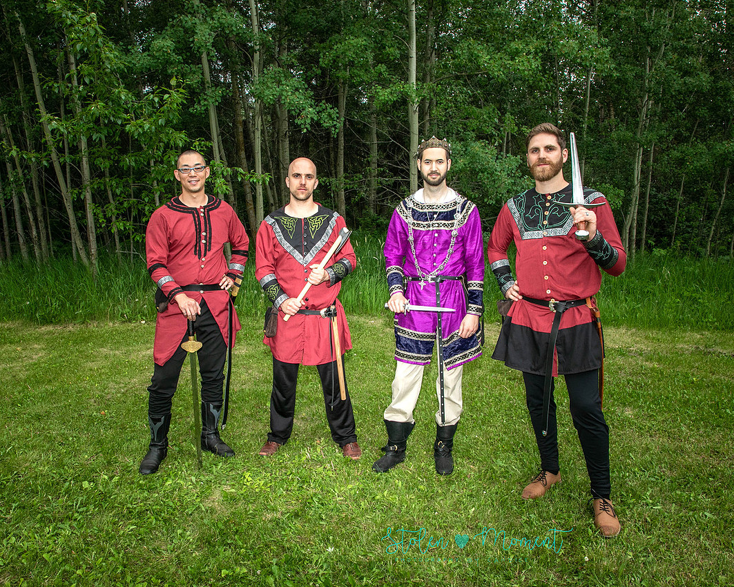 the groom stands between his three guards all holding various fourteenth century weapons and dressed in fourteen century garb.