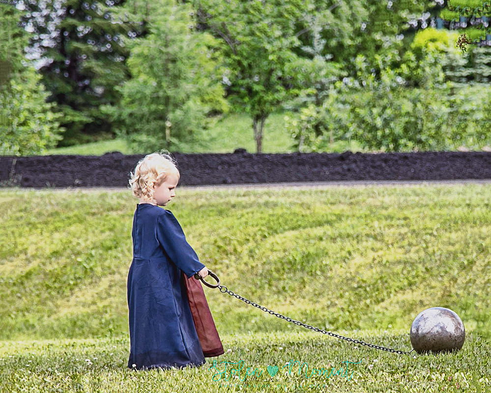 a little girl dressed in medieval costume pulls along a "ball and chain" during a medieval wedding reception outdoors