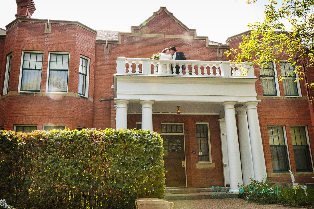 the bride and groom share a kiss outside on the balcony at Rutherford House 