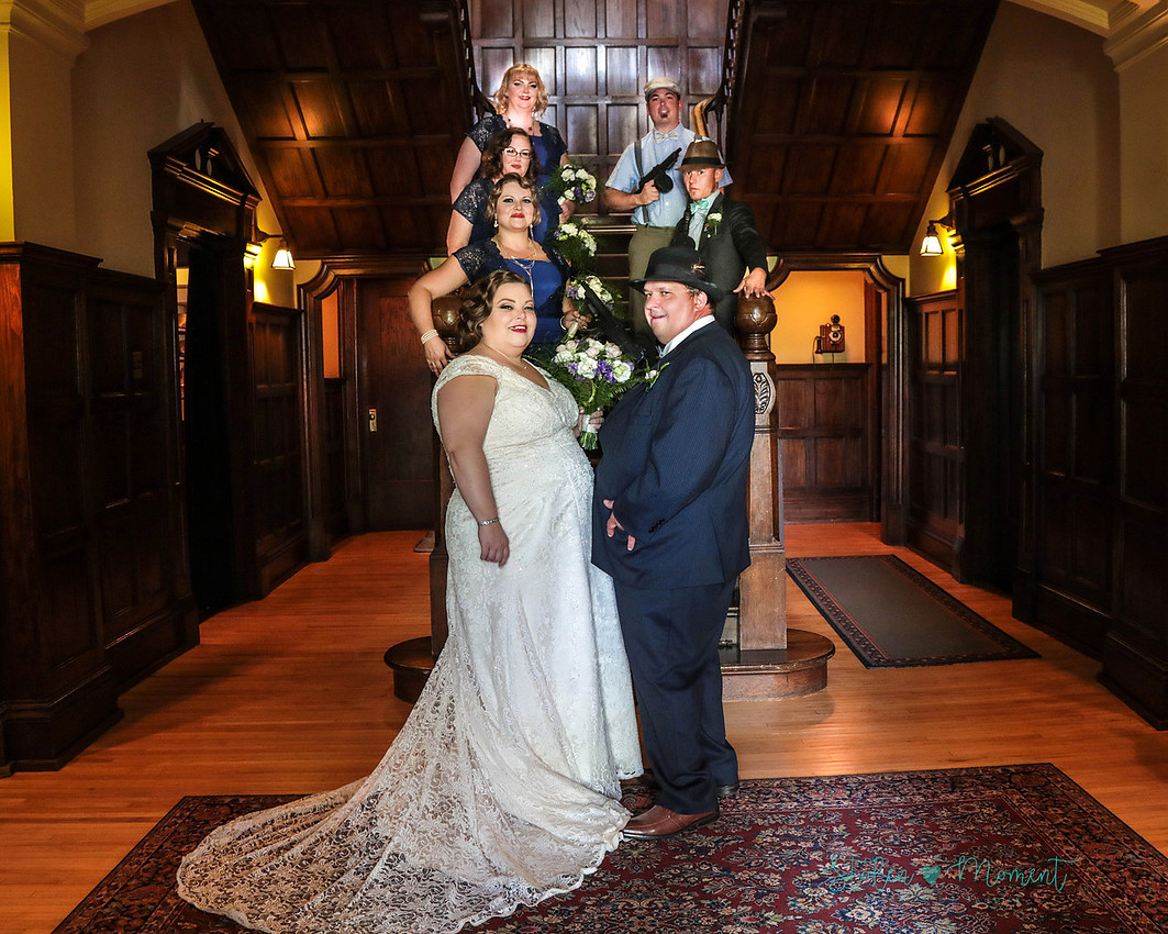 the bride, groom and the five members of their wedding party stand on the stairs inside Rutherford House