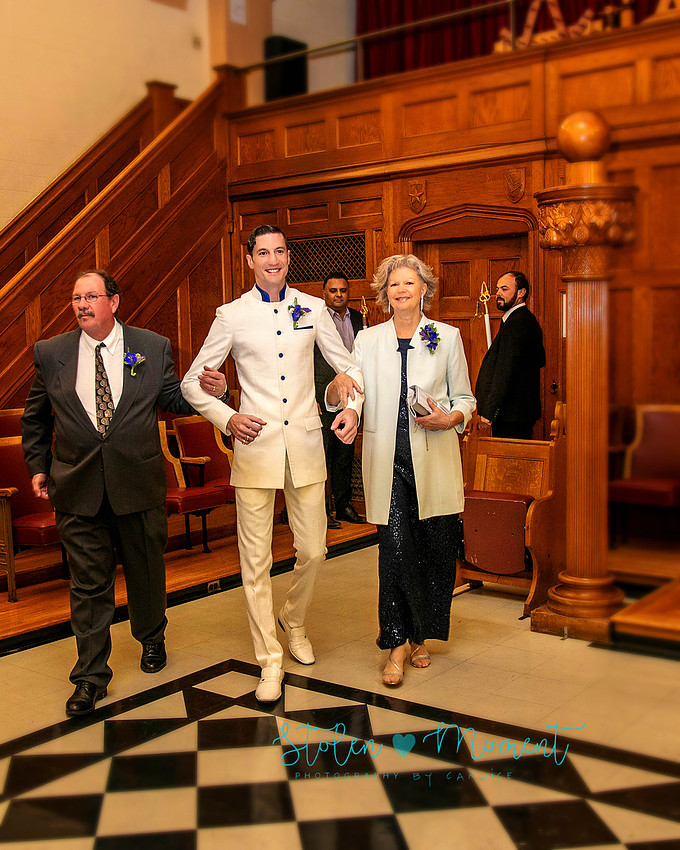 a bride in an elegant wedding dress and a groom in a white Indian suit are married at The Freemason hall in Edmonton with formals at Government House and Roger's Place on a snowy September day.