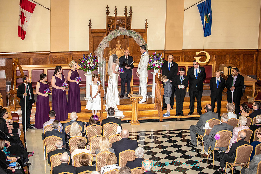 a bride in an elegant wedding dress and a groom in a white Indian suit are married at The Freemason hall in Edmonton with formals at Government House and Roger's Place on a snowy September day.