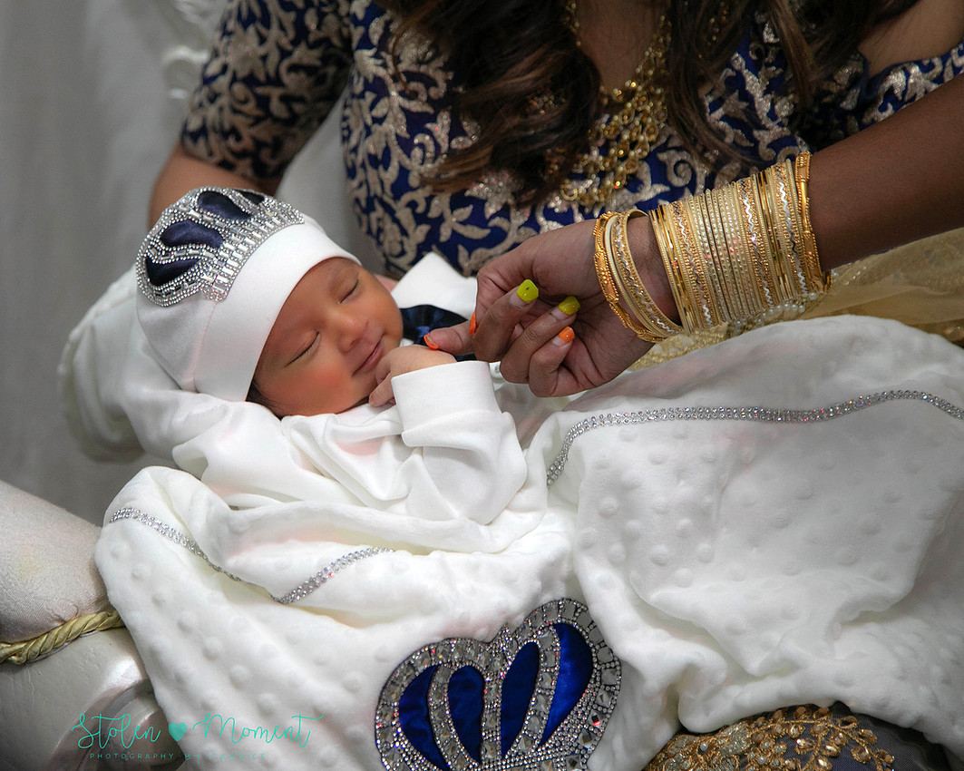 mom, dad and family celebrate the birth of a seven day old baby with hindu traditions.