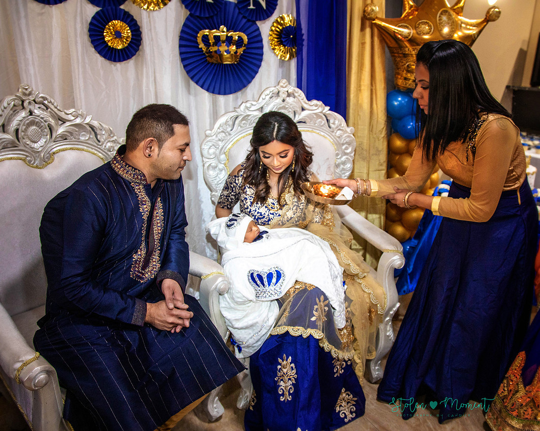mom, dad and family celebrate the birth of a seven day old baby with hindu traditions.