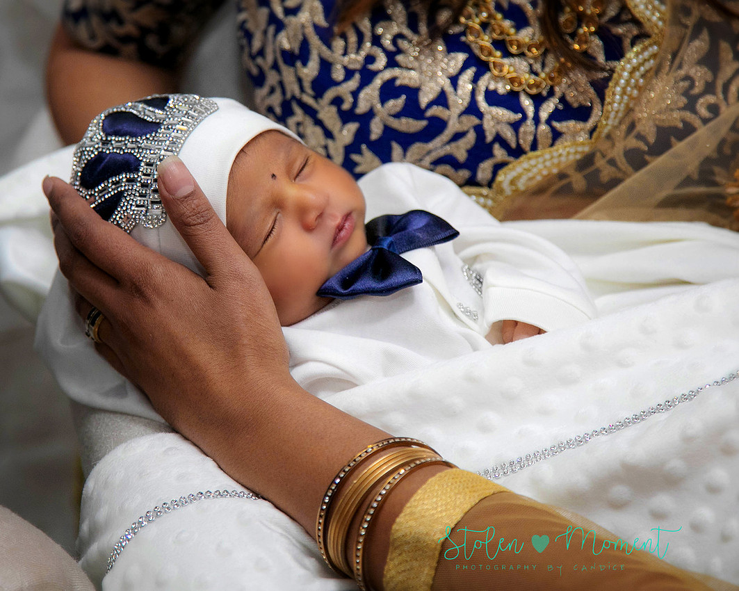 mom, dad and family celebrate the birth of a seven day old baby with hindu traditions.