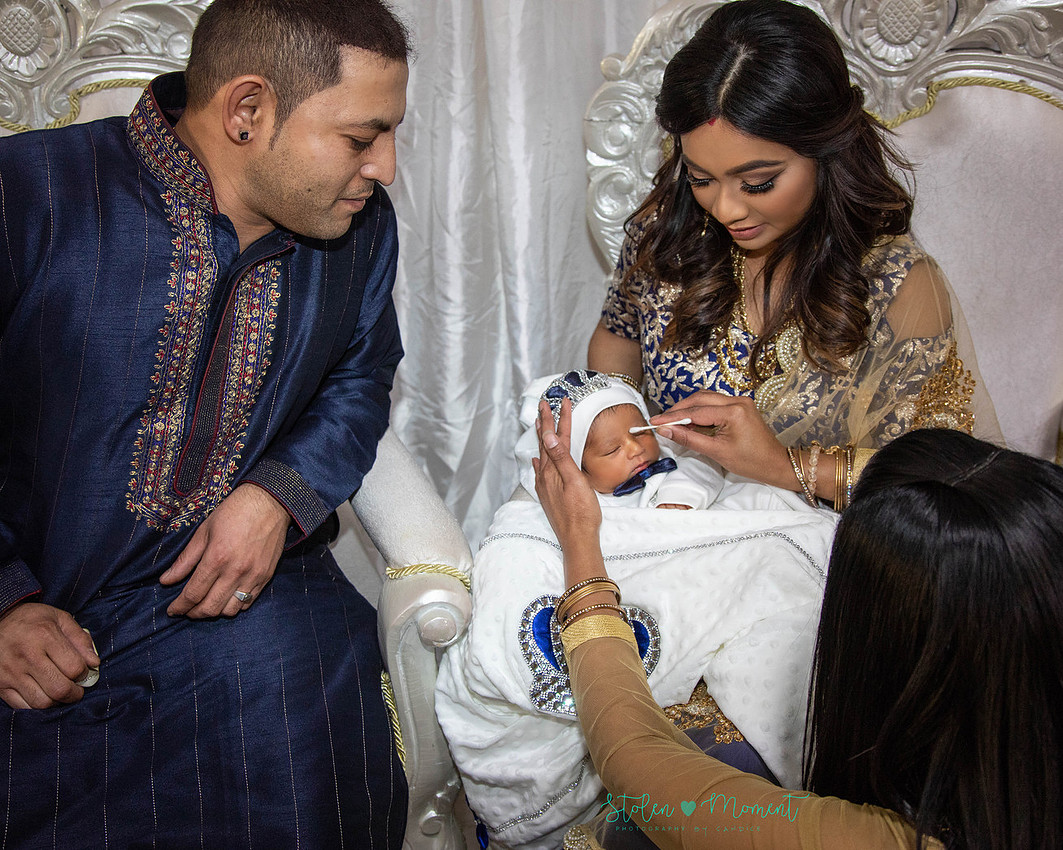 mom, dad and family celebrate the birth of a seven day old baby with hindu traditions.