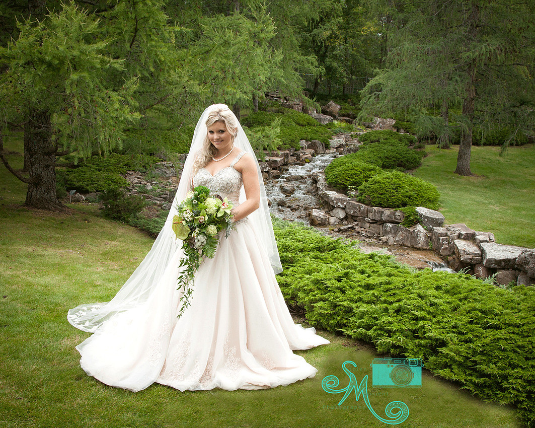 a beautiful bride stands in front of the falls at the Japanese Gardens
