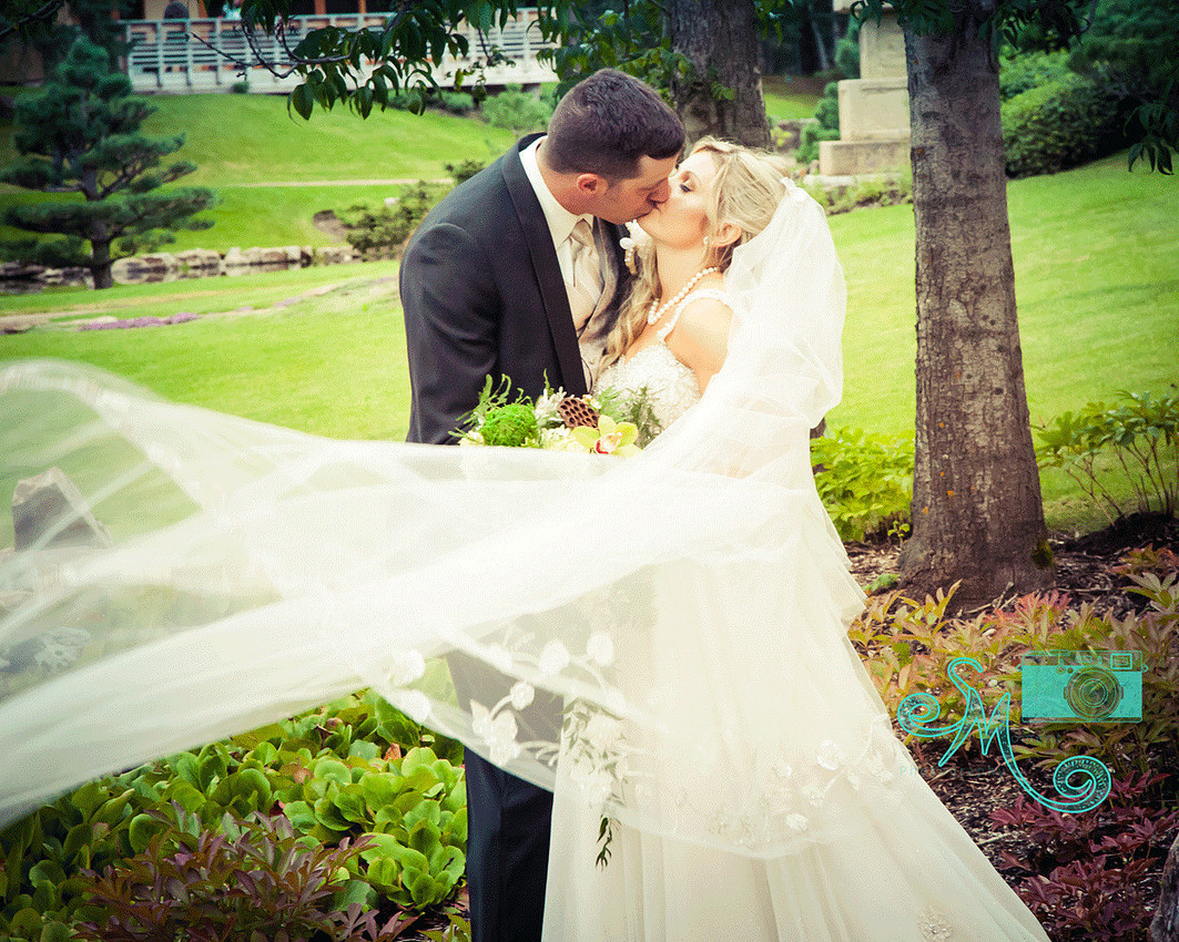 stunning photo of bride and groom kissing with veil blowing in the wind
