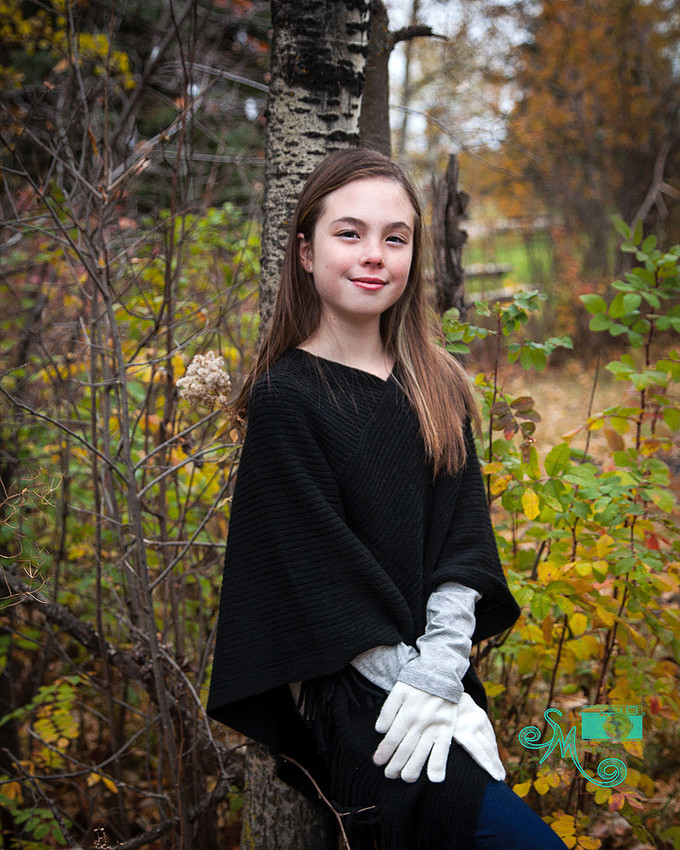 a young girl poses against a birch tree in the fall