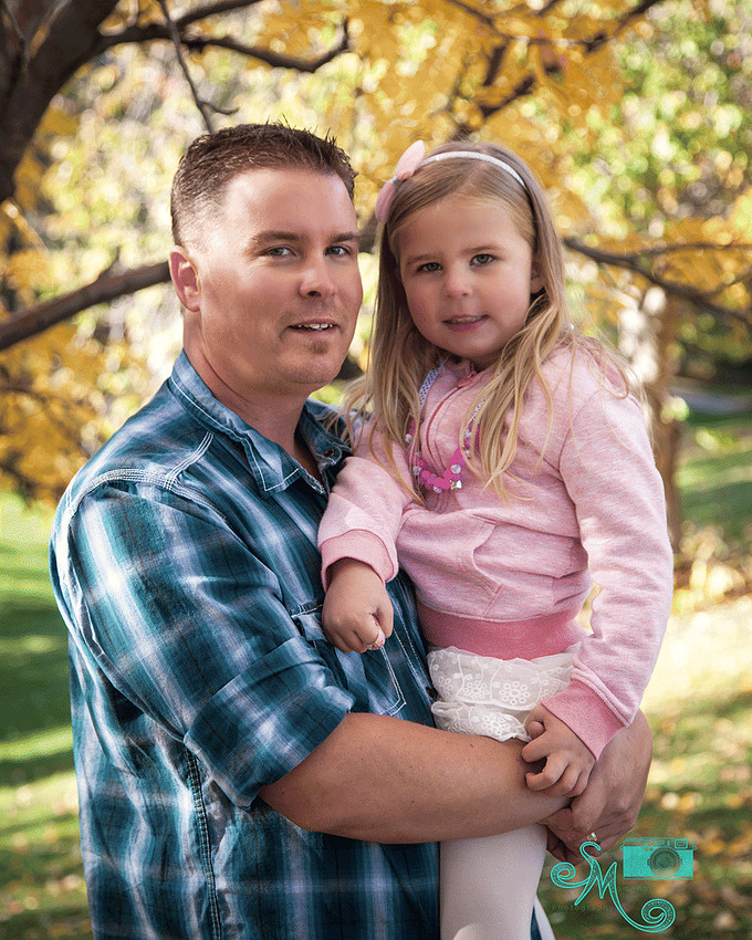dad and his little girl smile at camera with fall leaves in background