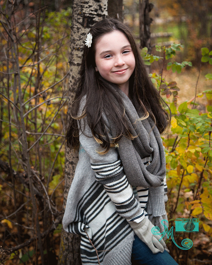 a young girl poses against a birch tree in the fall