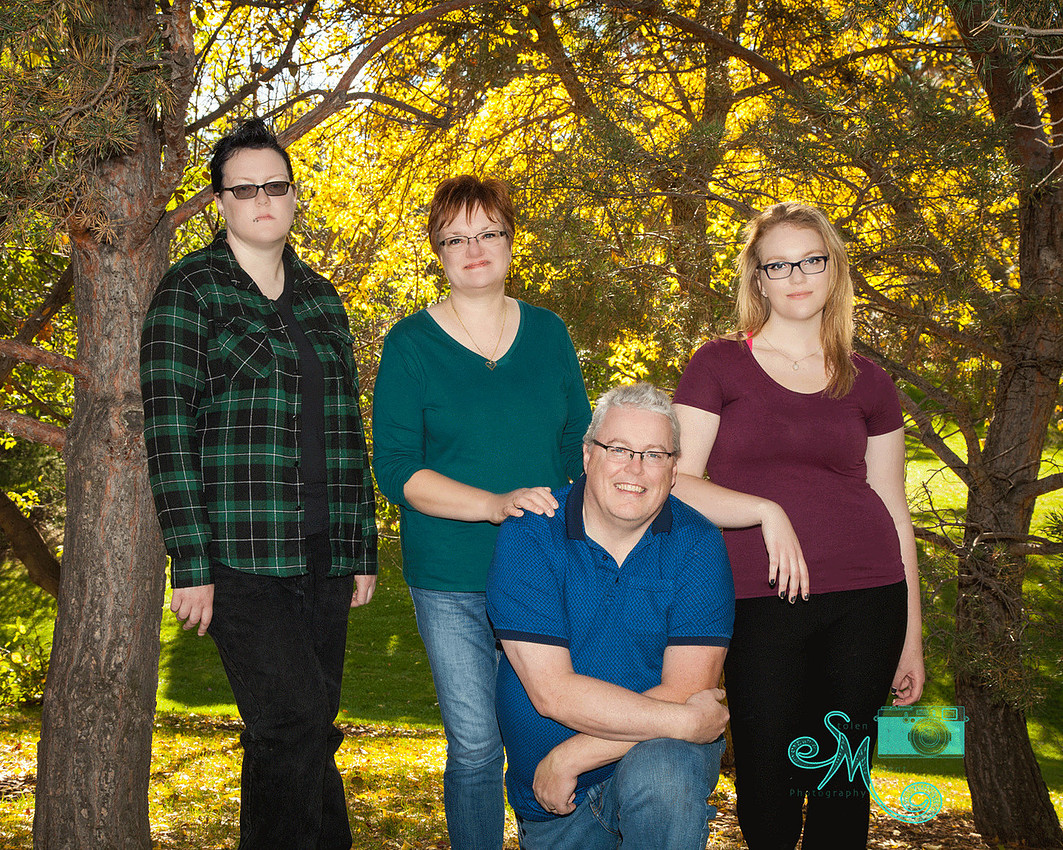 Family of four posing in front of a bunch of yellow coloured trees