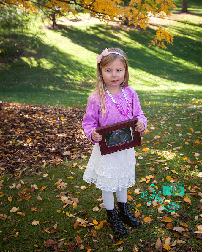 a little girl holds an ultrasound photo of her unborn sibling