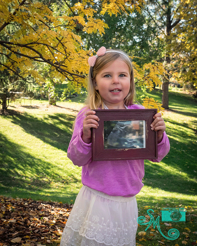 big sister to be poses holding an ultrasound photo