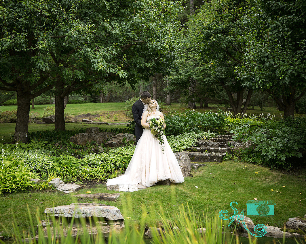 Bride and groom posing in an amazingly beautiful wooded, and rocky location at the Devonian Gardens